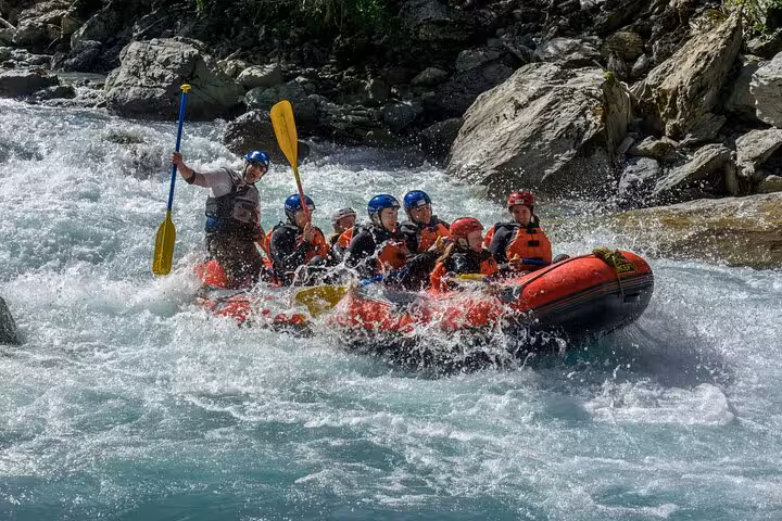 Group of rafters navigating thrilling rapids on a whitewater rafting adventure in Engadin, showcasing teamwork and excitement.
