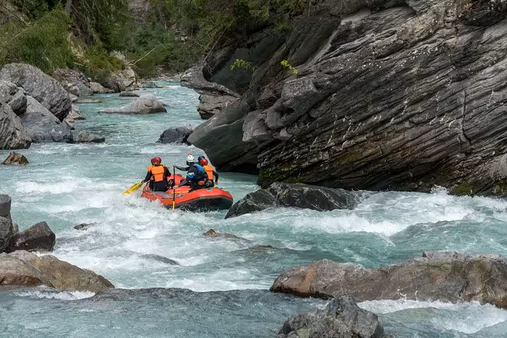 Rafters skillfully maneuvering through rocky Engadin river gorge, experiencing an exhilarating whitewater adventure.