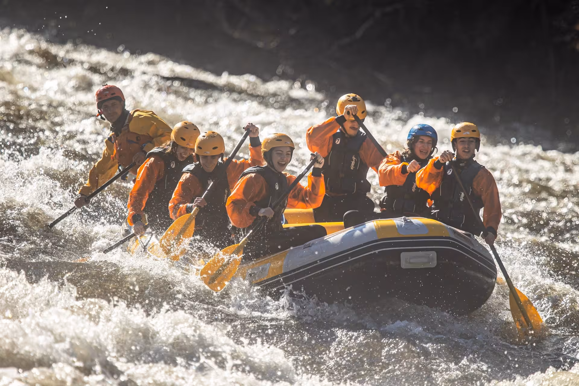 Group whitewater rafting Paiva River from Porto, paddling through rapids in Portugal with helmets and wetsuits
