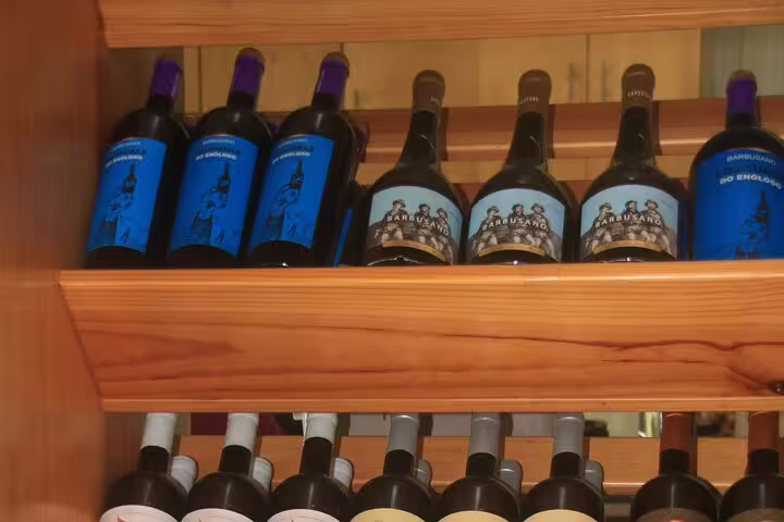 Wine bottles displayed on wooden shelves, part of a bestselling wine tour and tasting experience with 4x4 adventure and skywalk.