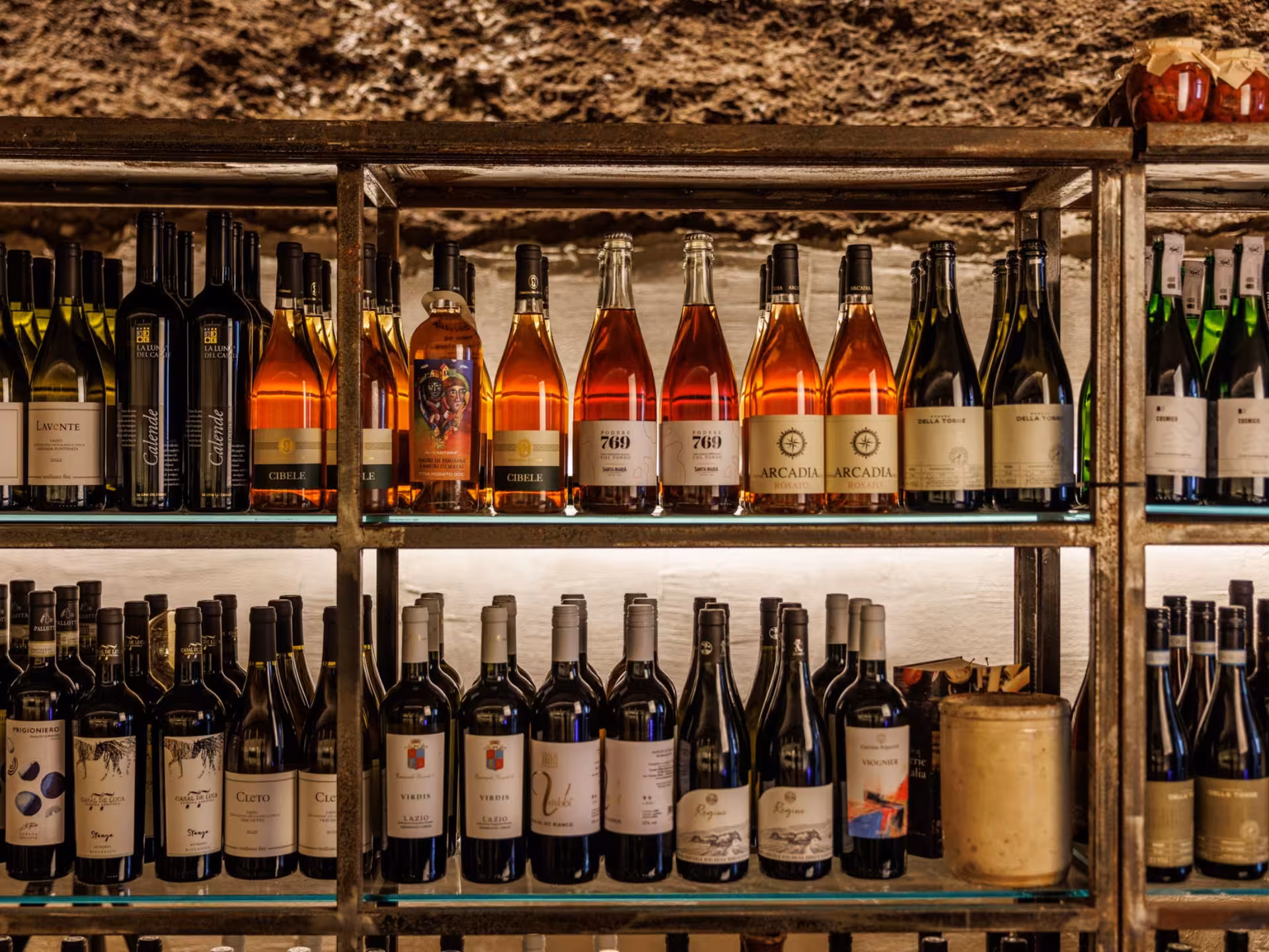 Shelves filled with assorted wine bottles in an underground cellar in Rome, perfect for a wine tasting experience.