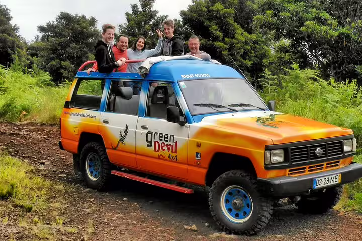 Group enjoying a scenic Wine & Cabo Girão Jeep Safari in Madeira, exploring lush landscapes in a colorful 4x4 adventure vehicle.