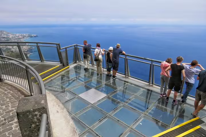 Visitors enjoy breathtaking ocean views from the Cabo Girão skywalk on a scenic Wine & Jeep Safari tour in Madeira.