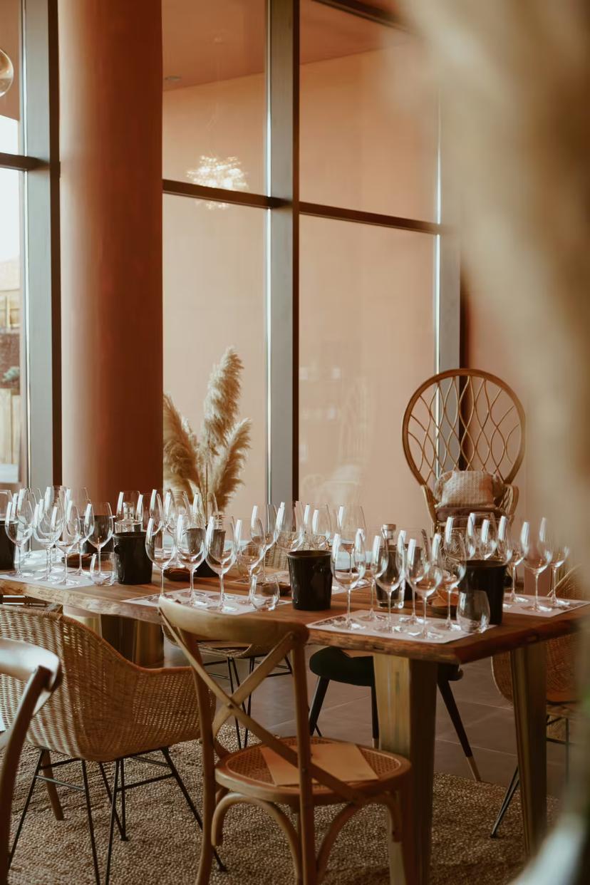 Elegant wine tasting setup with glasses and rustic decor in a sunlit room, perfect for a premium tasting event.