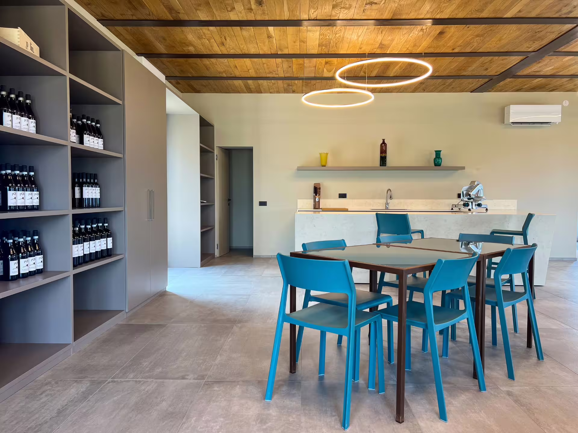 Elegant wine tasting area near Alba featuring blue seating, contemporary decor, and shelves of fine wines.