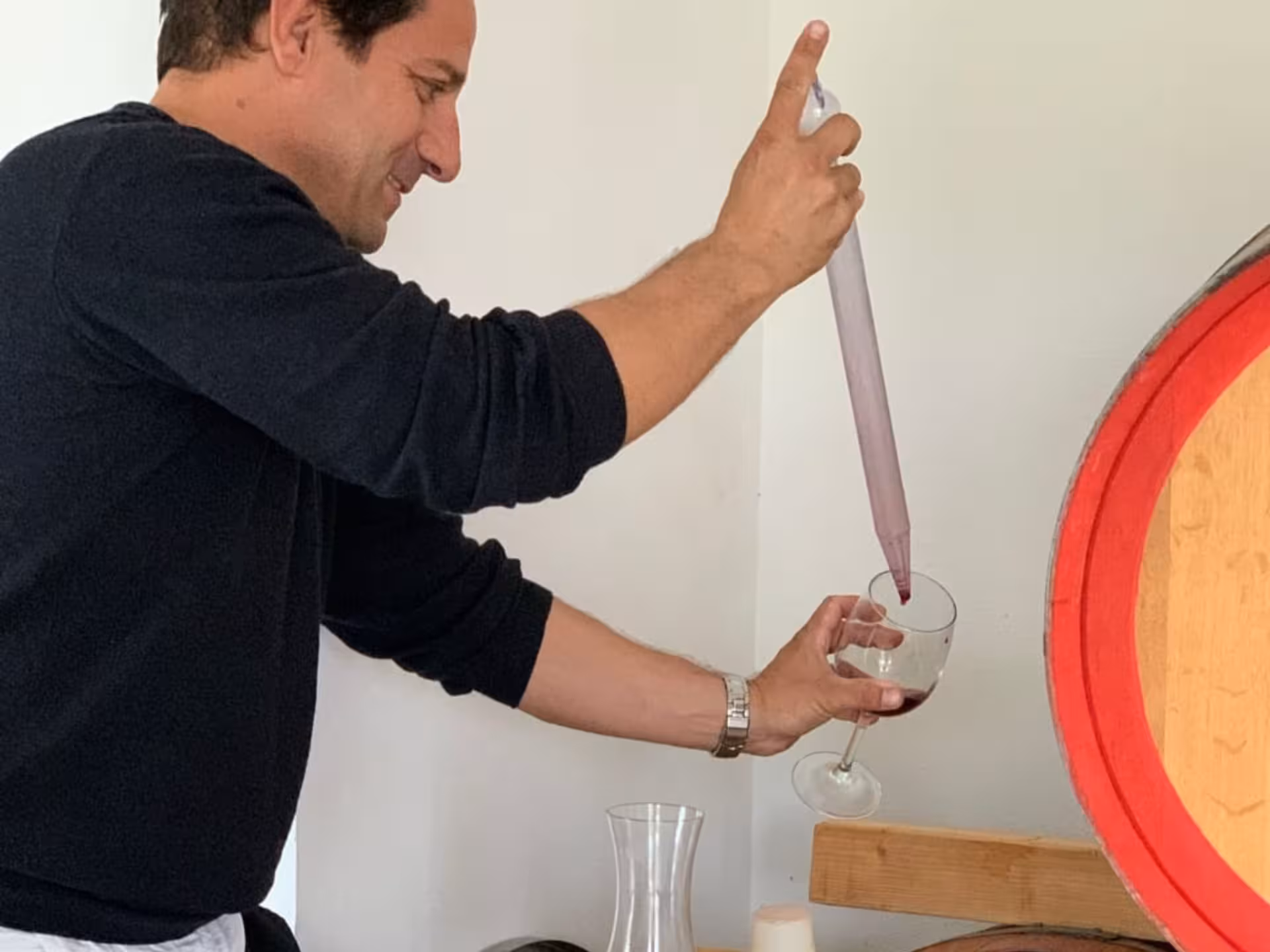 Man expertly siphoning wine from a barrel into a glass, showcasing the wine tasting experience near Cagliari.