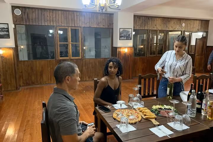 Guests experiencing a wine tasting session with food pairing at a cozy venue in Berat, hosted by a local guide.