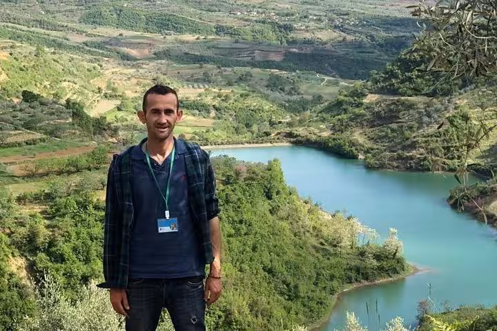 Guide smiling in front of a picturesque landscape of vineyards and hills in Berat on the Wine Tasting & Food tour.