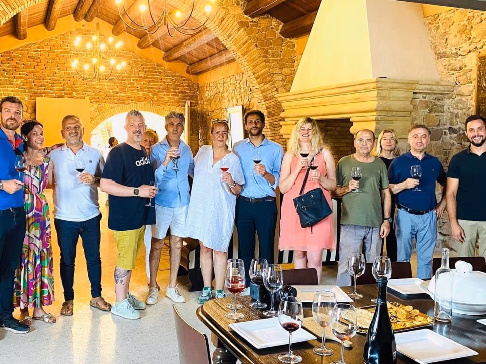 Group of people enjoying wine tasting inside a rustic Cagliari countryside winery with stone walls.