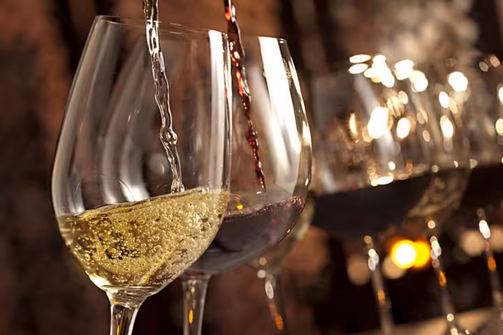 Close-up of red and white wine being poured into glasses, showcasing a wine tasting experience in Cannes.