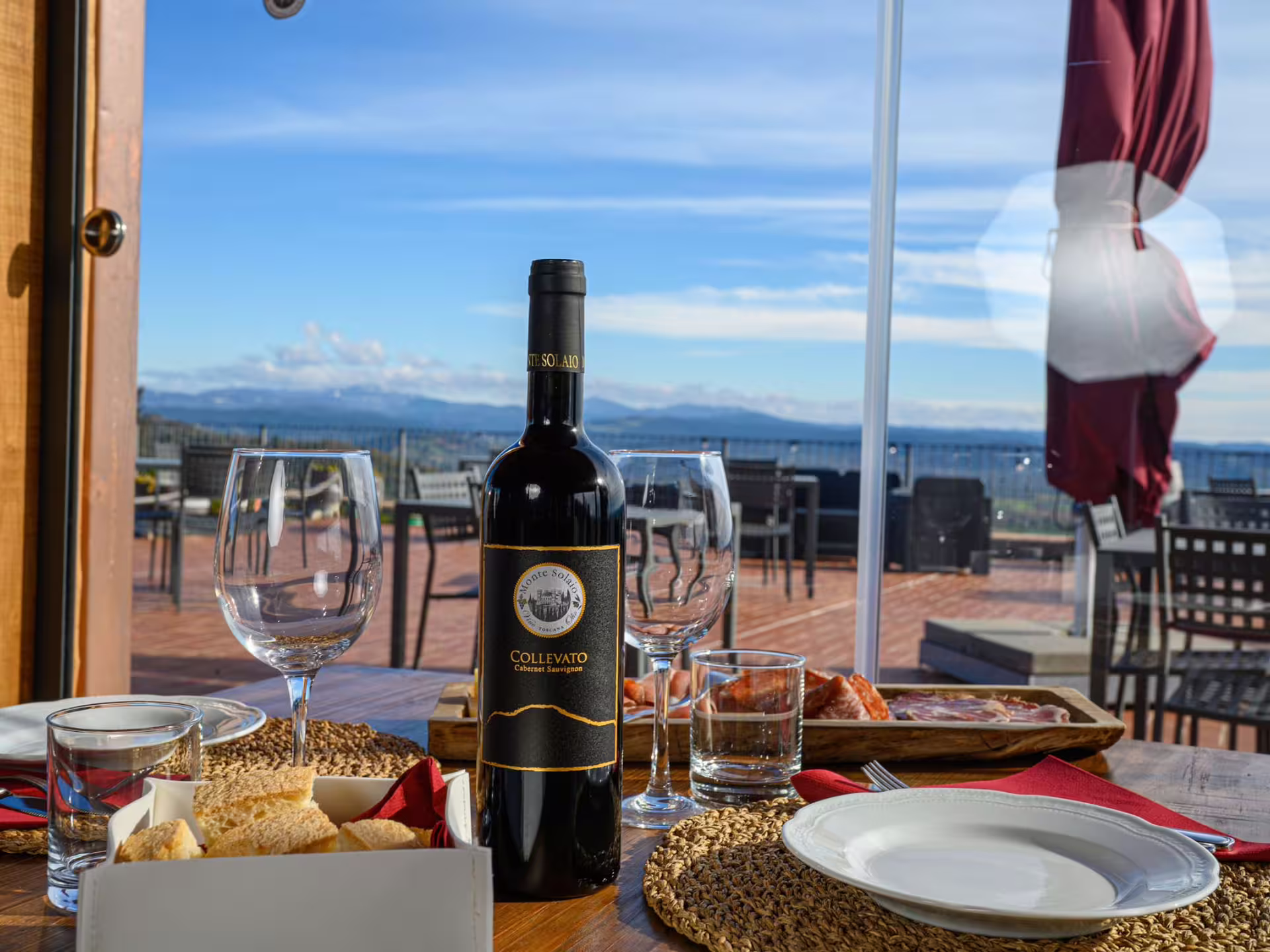 Elegant wine and charcuterie setup with stunning vineyard backdrop for a memorable wine tasting near Livorno.