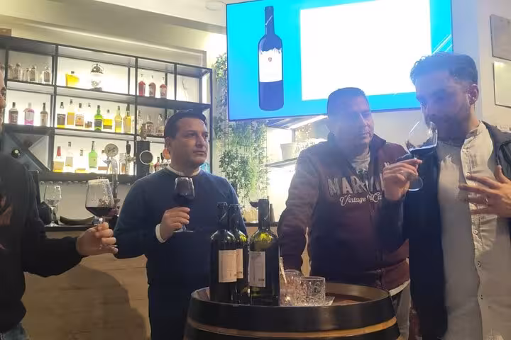 Group of participants engaged in a wine tasting course in Rome, exploring wine aromas and flavors in a vibrant setting.