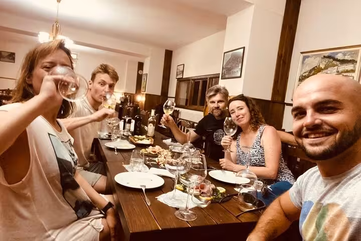 Group enjoying a wine tasting dinner in Berat, featuring local wines and a cozy atmosphere.