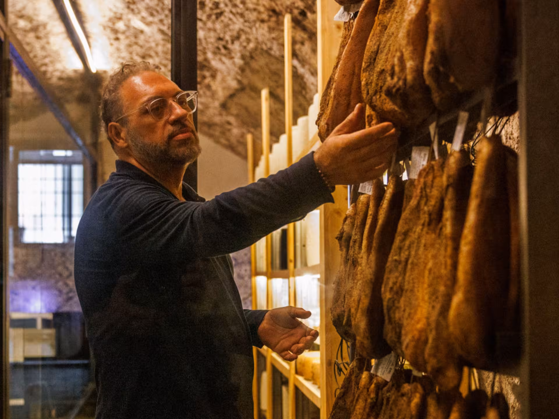 Man examining cured meats in a Roman underground cellar, part of a wine tasting and food pairing tour.