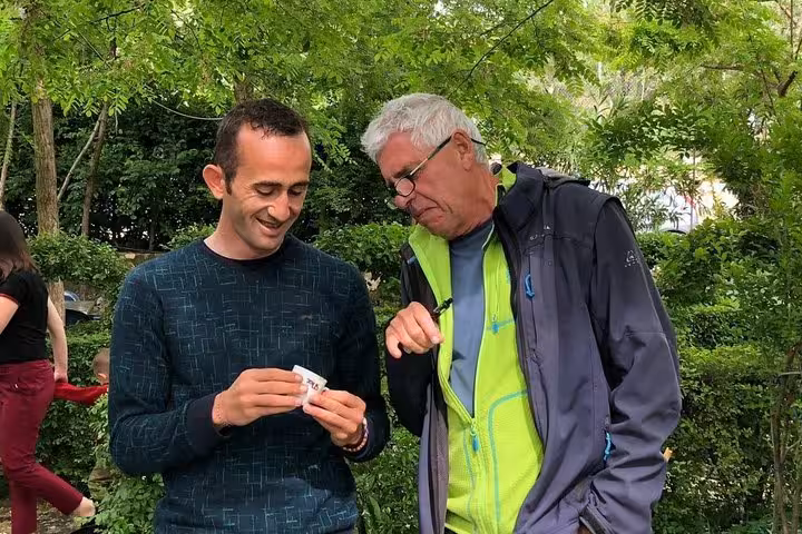 Guests enjoying a moment at the Wine Tasting & Food tour in Berat, surrounded by lush greenery and engaging conversation.