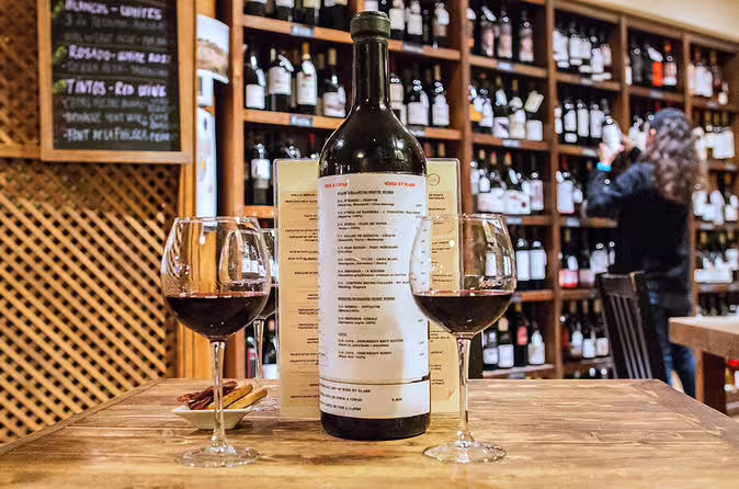 Wine tasting setup with two glasses and a bottle in a wine shop, perfect for a Tapas & Wine Experience.