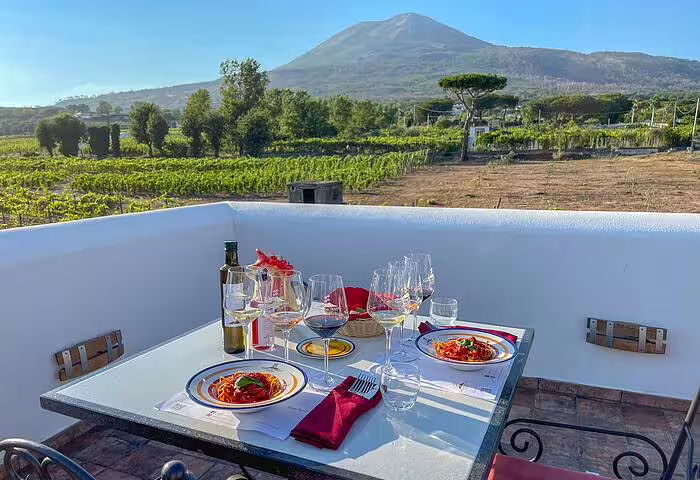 Elegant vineyard terrace table set with wine glasses and lunch, with Mount Vesuvius views on a luxury tasting tour