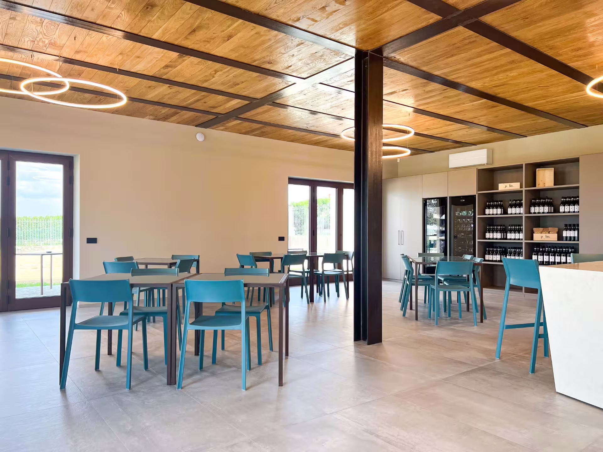 Modern wine tasting room in Langhe with blue chairs, wooden ceiling, and wine display, ideal for gourmet pairings.