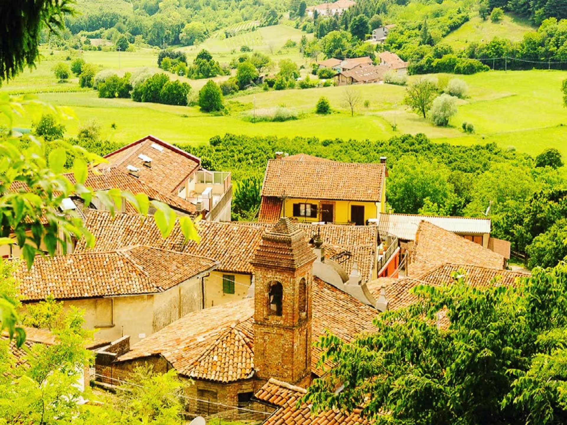 Scenic view of a charming village with terracotta roofs nestled in lush greenery near Asti and Turin.