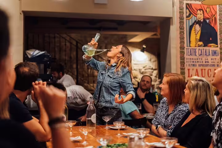 Tour guide demonstrating traditional wine pouring technique to an engaged group in a cozy tapas bar.