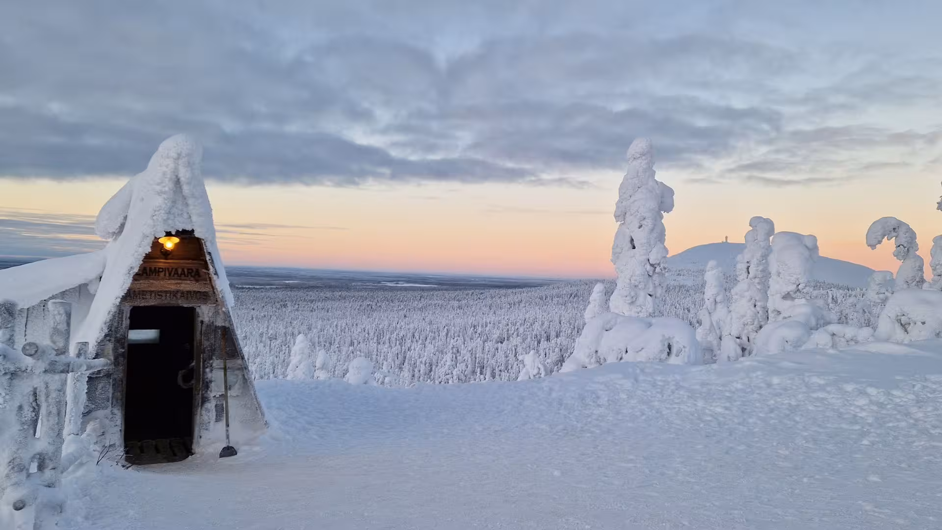 Snowy landscape with a rustic cabin and frosty trees at sunset, ideal for the Lapland Amethyst Mine adventure.