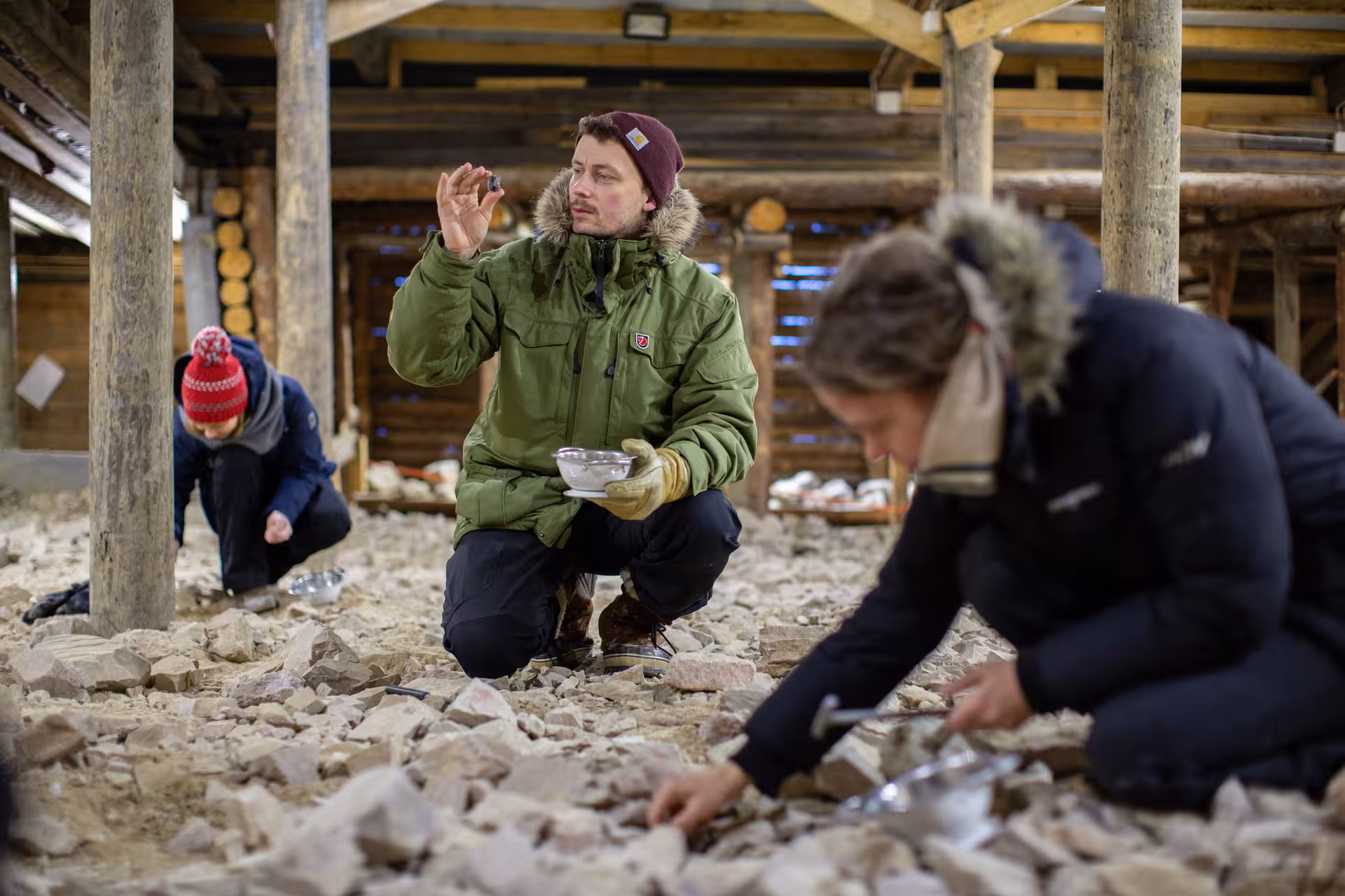 Participants search for amethyst in a rustic indoor setting during the Winter Amethyst Mine Experience in Lapland.