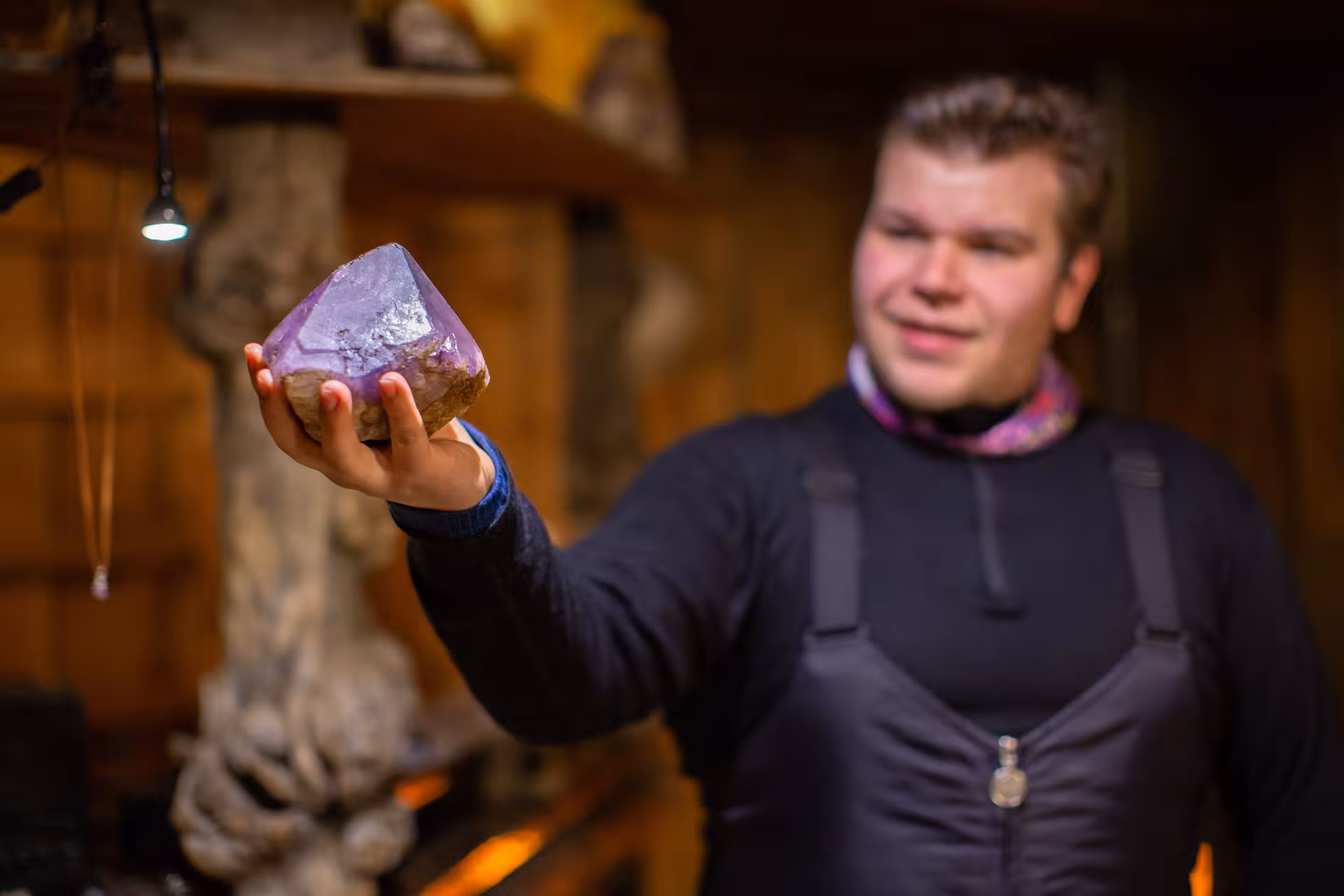 A person admires a large, raw amethyst gemstone during the Winter Amethyst Mine Experience in Lapland.
