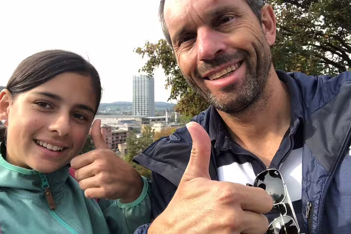 Happy travelers give thumbs up with Winterthur skyline viewpoint on a self-guided scavenger hunt tour