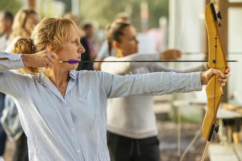 Woman practicing archery in Weesp with recurve bow and arrow, guided outdoor target session near Amsterdam