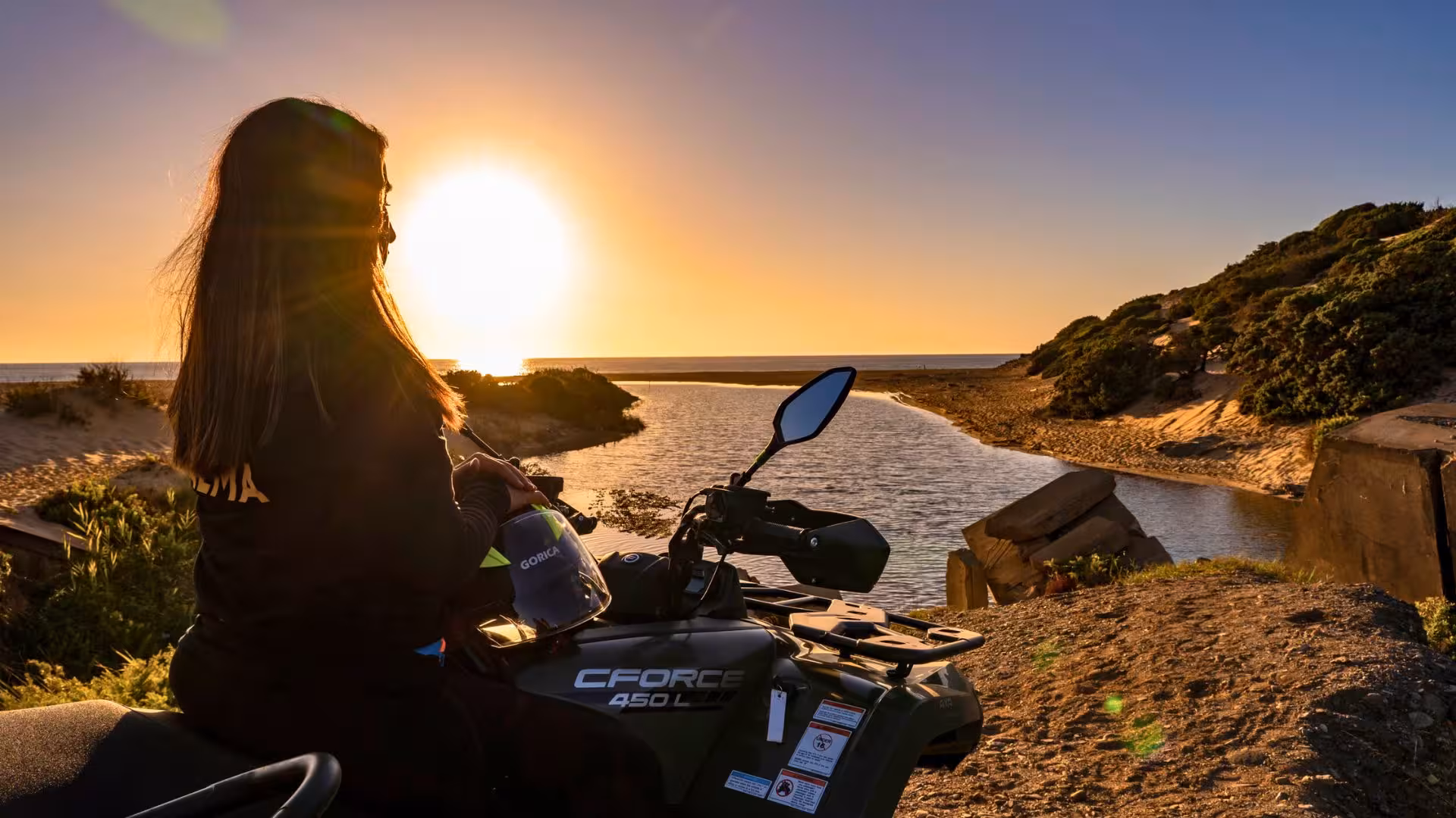 Woman on ATV enjoying a stunning sunset view over Costa Verde's coastline during an adventurous excursion.