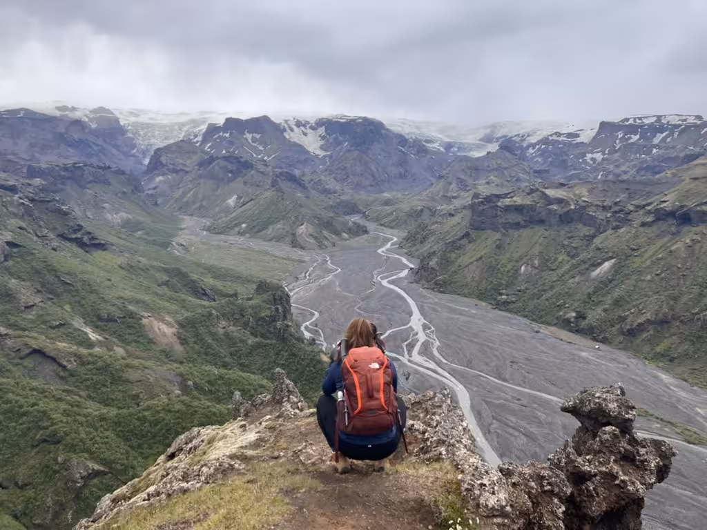Woman with backpack overlooks Þórsmörk's dramatic valleys on a women-only hiking tour in Iceland.