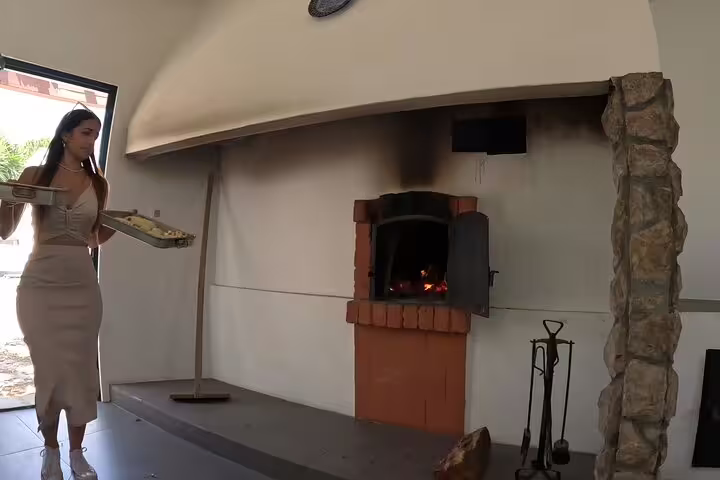 Woman preparing traditional bread in a rustic stone oven, showcasing authentic culinary experiences in a cozy kitchen.