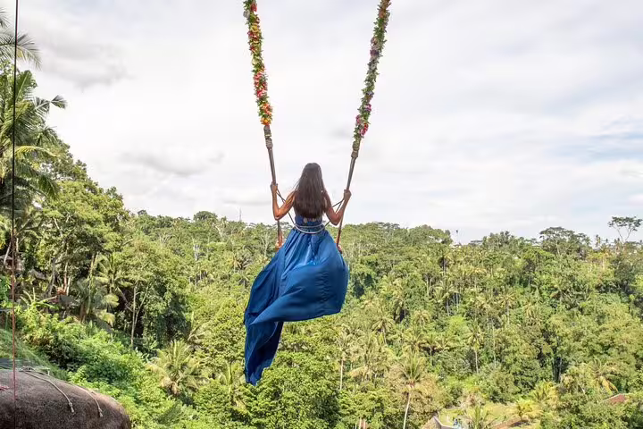 Woman on Bali jungle swing in blue dress captured by private vacation photographer for iconic Ubud photos