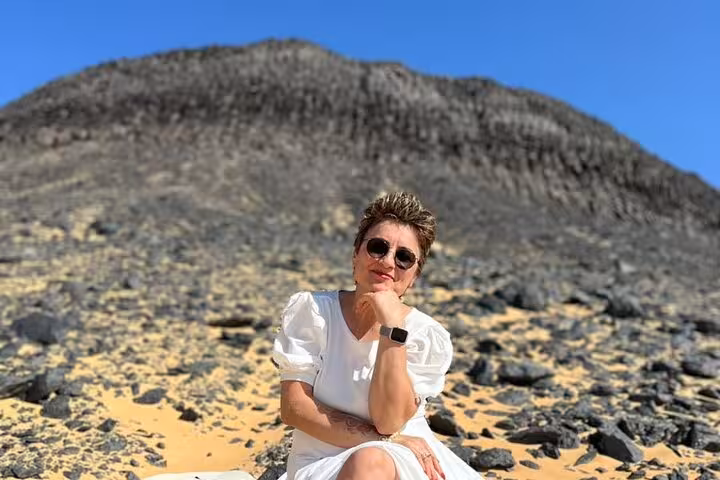 Woman posing at Black Desert volcanic hill on private 2-day Black and White Desert safari with camping