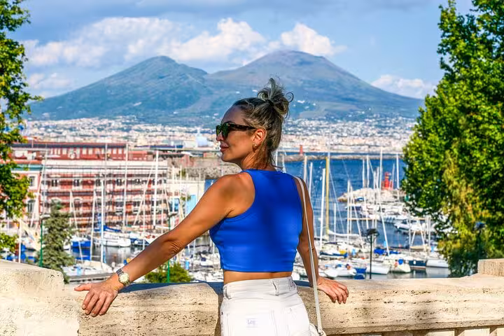 Woman in blue top enjoys scenic view of Naples harbor and Mount Vesuvius during a private photo shoot.