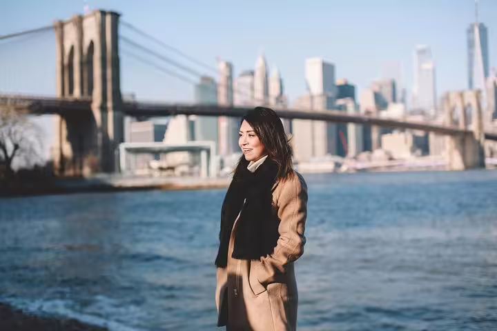 Smiling woman poses by Brooklyn Bridge on New York travel photography tour.