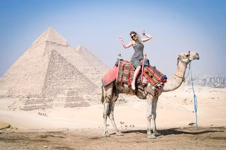 Woman enjoying a free camel ride near the Pyramids of Giza on a Cairo full-day customized private tour