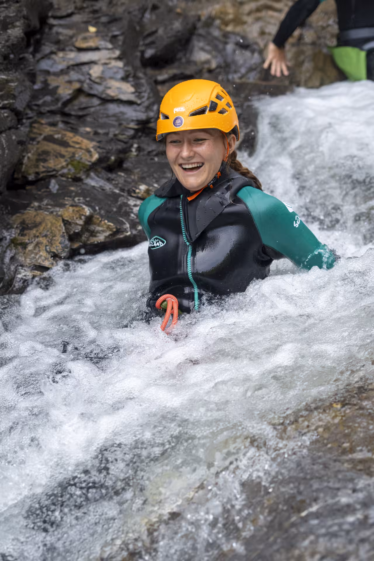 Smiling woman enjoys thrilling canyoning experience in bubbling waters of Interlaken, wearing safety gear.
