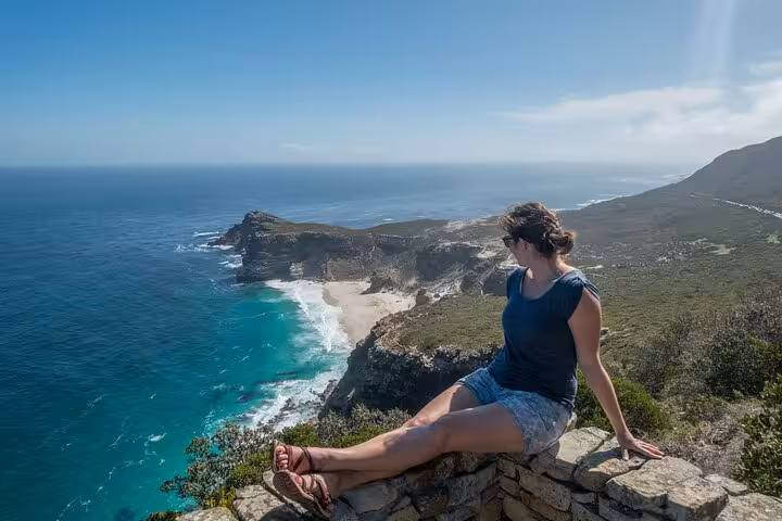 Woman enjoying stunning coastal views at Cape of Good Hope, showcasing ocean vistas and rugged cliffs.