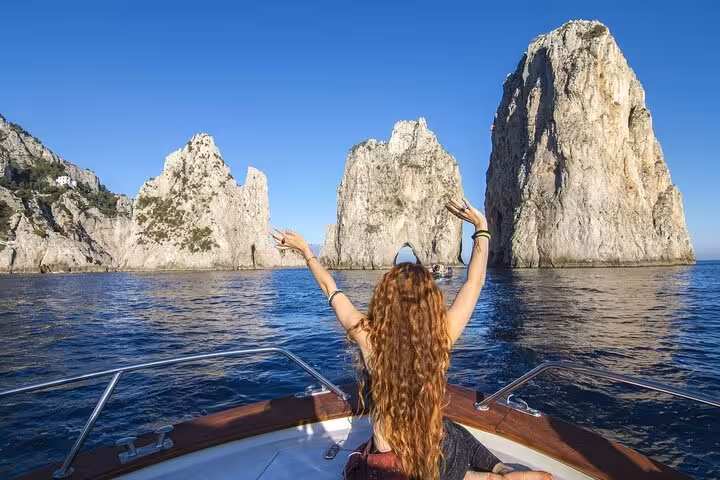 Woman enjoying stunning view of Capri's Faraglioni rocks from boat on Amalfi Coast tour.