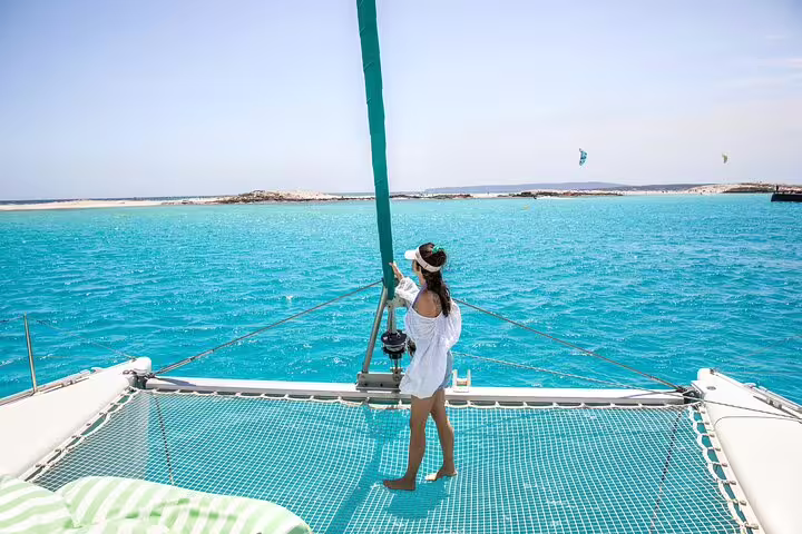Woman enjoying a sunny day on a catamaran in the turquoise waters of Formentera and Ibiza during a small group sailing trip.