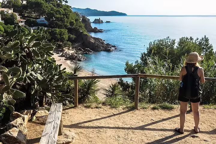 Woman admires scenic coastal views from a cliffside path in Costa Brava during Dalí tour.