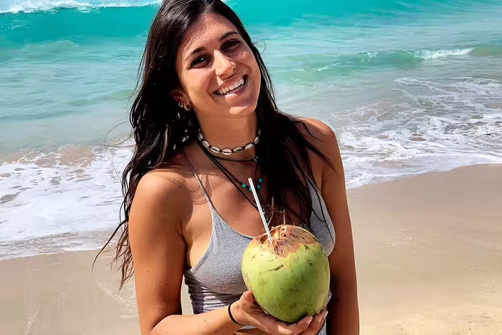 Woman enjoying a fresh coconut on the pristine beach of Boa Vista during a 7-day adventure tour.