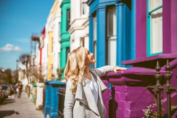Woman admires colorful row houses in London, perfect backdrop for a personal travel photographer tour.