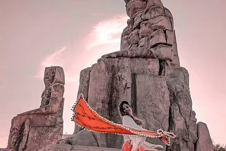 Woman with colorful shawl at the Colossi of Memnon, Luxor West Bank Nile tour with sunset over ancient Egypt