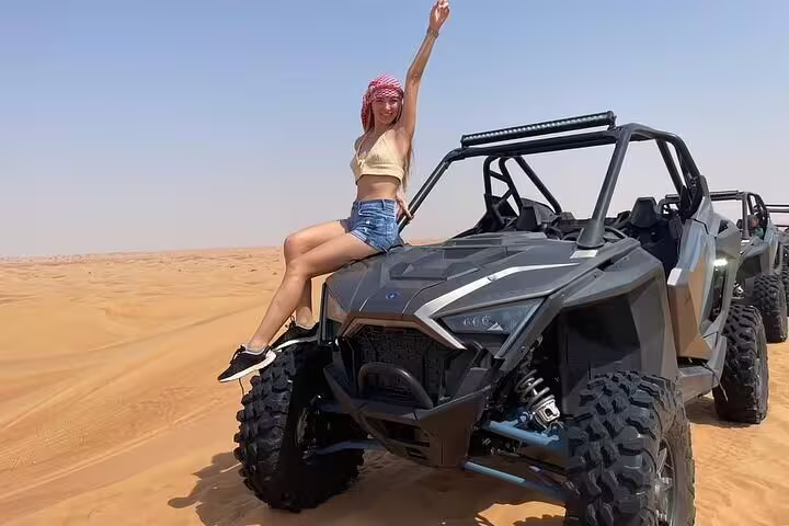 Adventurous woman enjoying a thrilling dune buggy ride in Dubai's expansive desert landscape.
