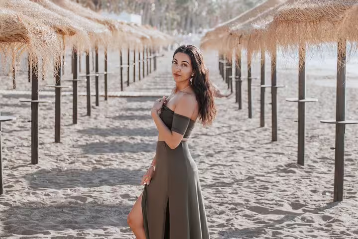 Woman posing elegantly under rustic beach parasols in Marbella, ideal location for a stylish photoshoot.