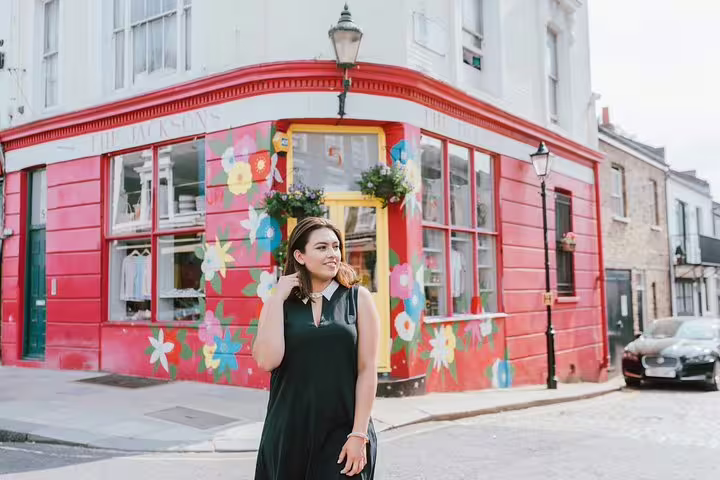 Woman poses by vibrant, flower-painted building in London, capturing unique moments on a private photo tour.