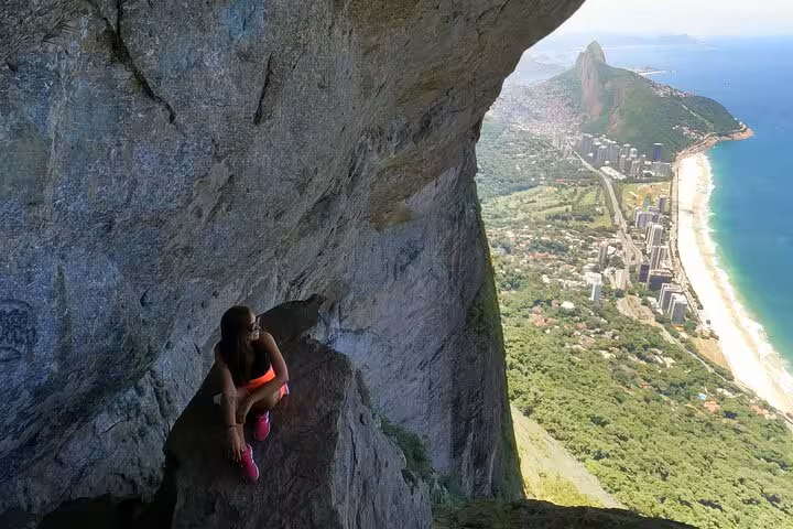 Woman sitting on a rock with stunning views of Rio de Janeiro's coastline from Garganta do Céu in Pedra da Gávea.