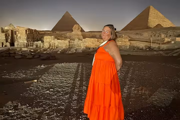 Woman posing by the Giza Pyramids at night, exclusive Cairo tour with camel ride, desert bike safari and Nile felucca